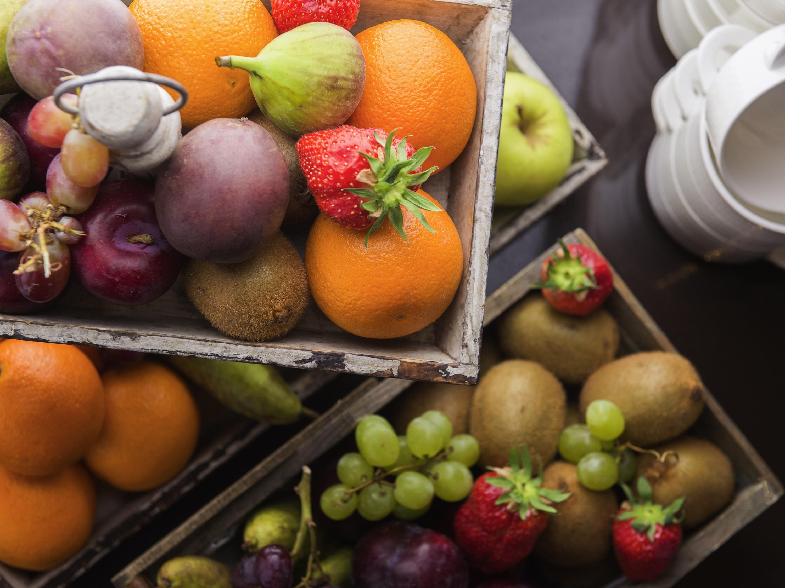 A wooden crate filled with various fruits including apples, oranges, and grapes.