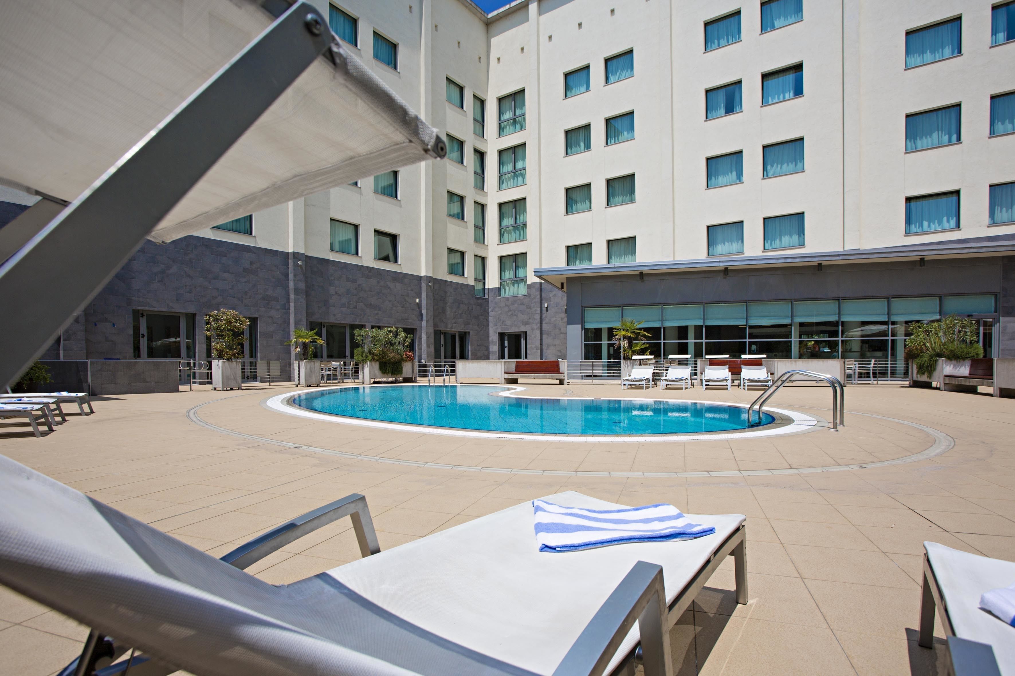 A pool area with lounge chairs and a building in the background.