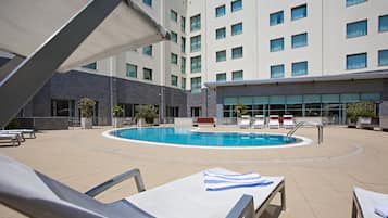 A pool area with lounge chairs and a building in the background.