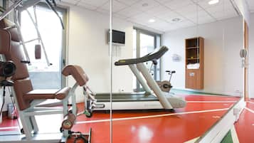 A gym with exercise equipment, a treadmill, and a mirrored wall.