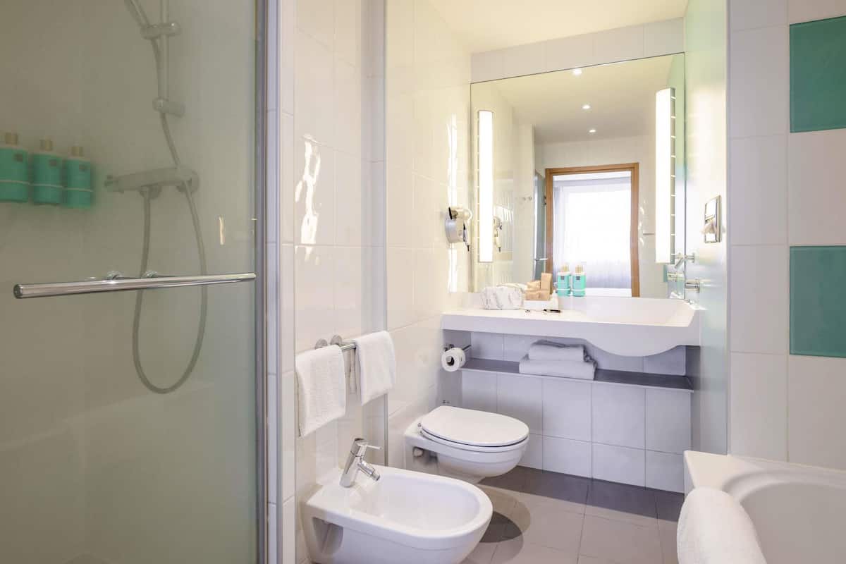 A modern bathroom with a glass shower enclosure, a sink, a toilet, and a bathtub.