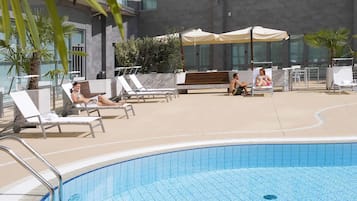 Alberca al aire libre, sombrillas en la alberca y camastros