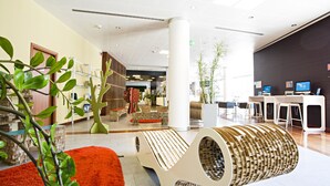 Een moderne lobby met een unieke zithoek, een receptiebalie en een groot raam dat voor daglicht zorgt.