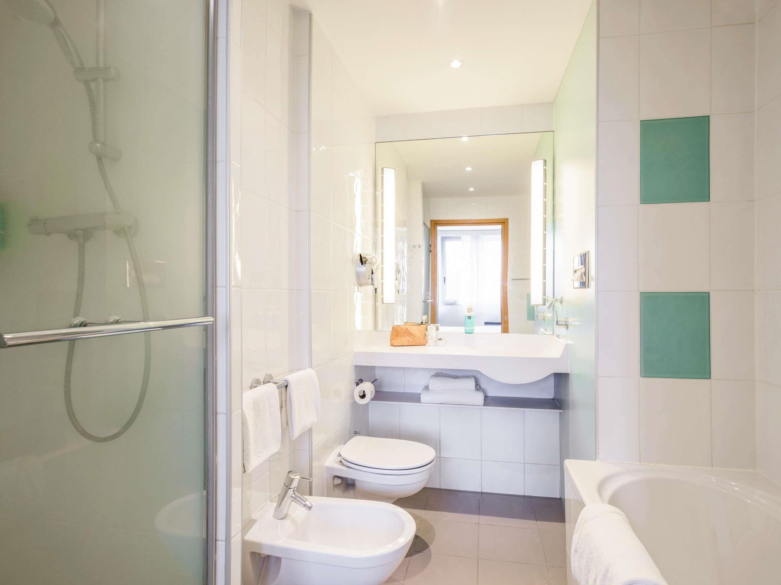 Un baño moderno con cabina de ducha de vidrio, lavabo blanco, inodoro y bañera.
