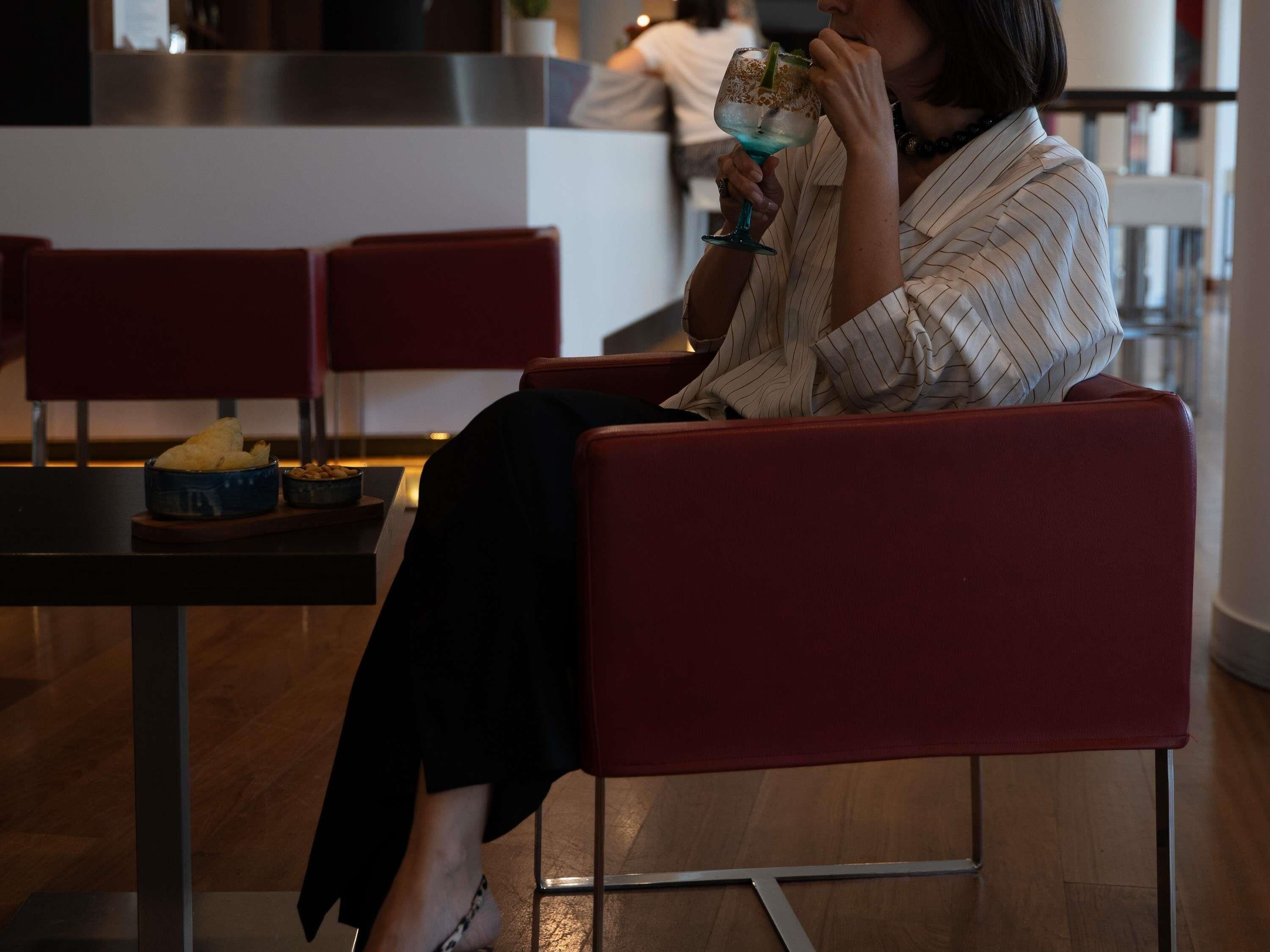 A person seated on a red chair in a modern interior with a table in front.