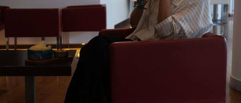 A person seated on a red chair in a modern interior with a table in front.