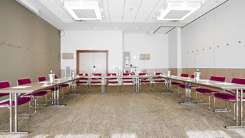 A conference room with a long table, red chairs, and white walls.