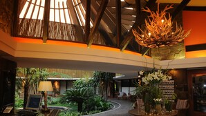 A lobby with a curved pathway, a reception desk, a chandelier, and indoor plants.