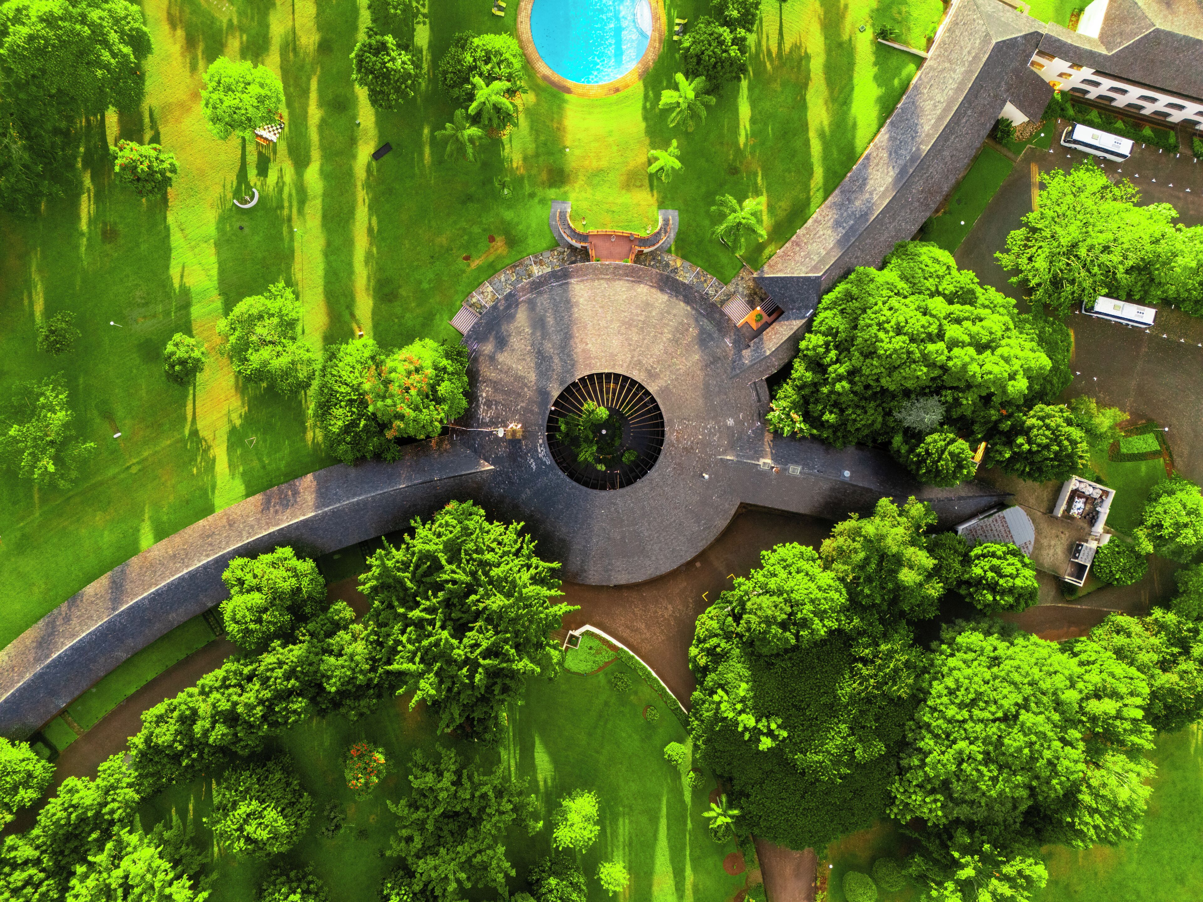An aerial view of a park with a circular central feature, pathways, and greenery.