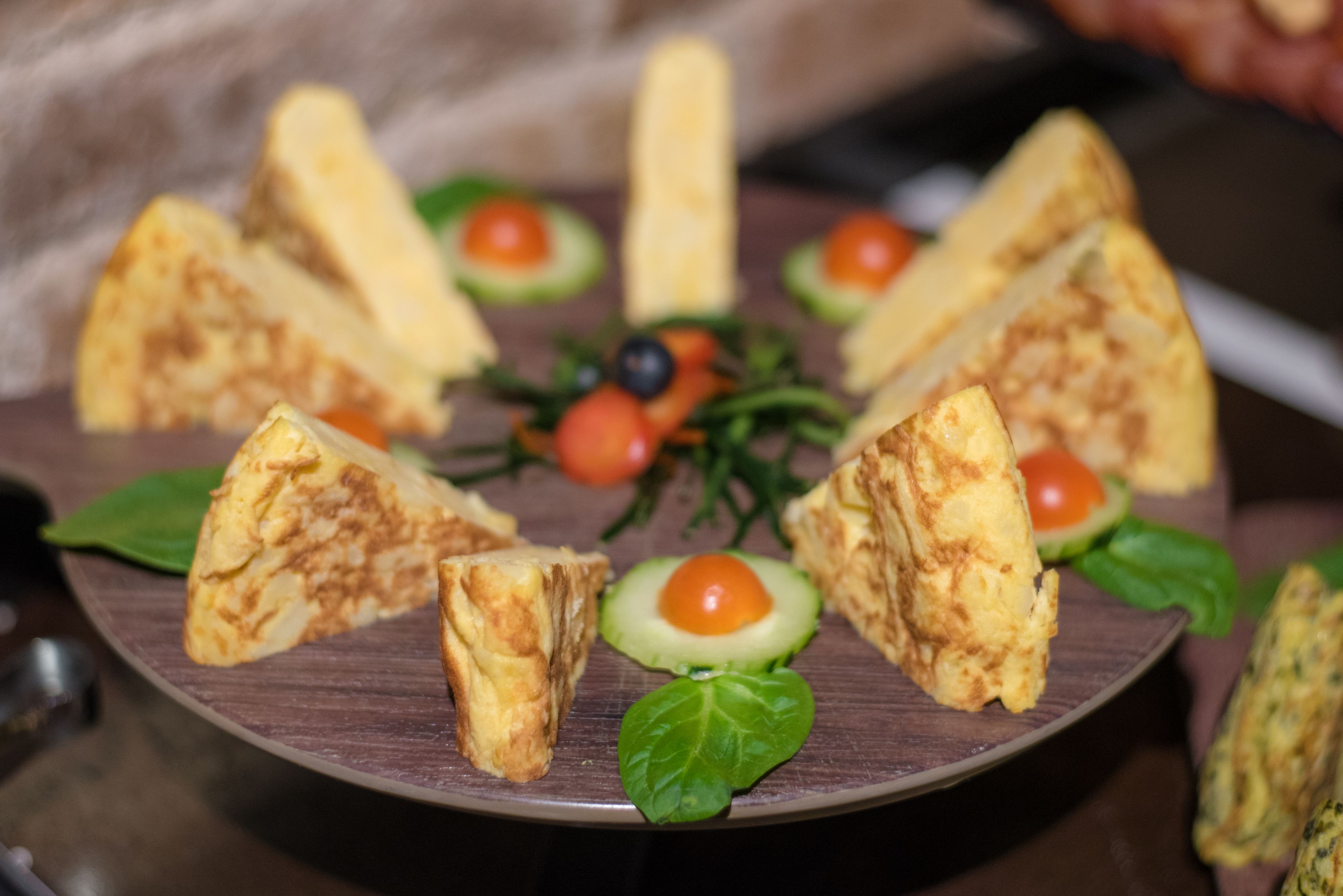 A plate of food with various items including avocado slices, cherry tomatoes, and leafy greens.