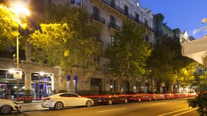 A street scene with a building featuring classical architecture, a parked car, and a tree-lined sidewalk. - Petit Palace Museum (Barcelona)