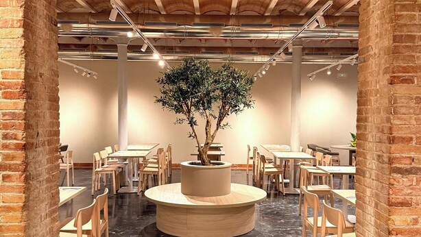 A restaurant with brick walls, a central tree planter, and a circular seating area. - Petit Palace Museum (Barcelona)