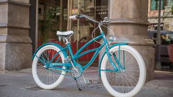 Una bicicleta turquesa estacionada frente a un edificio con un letrero que dice "PETIT PALACE MUSEUM".