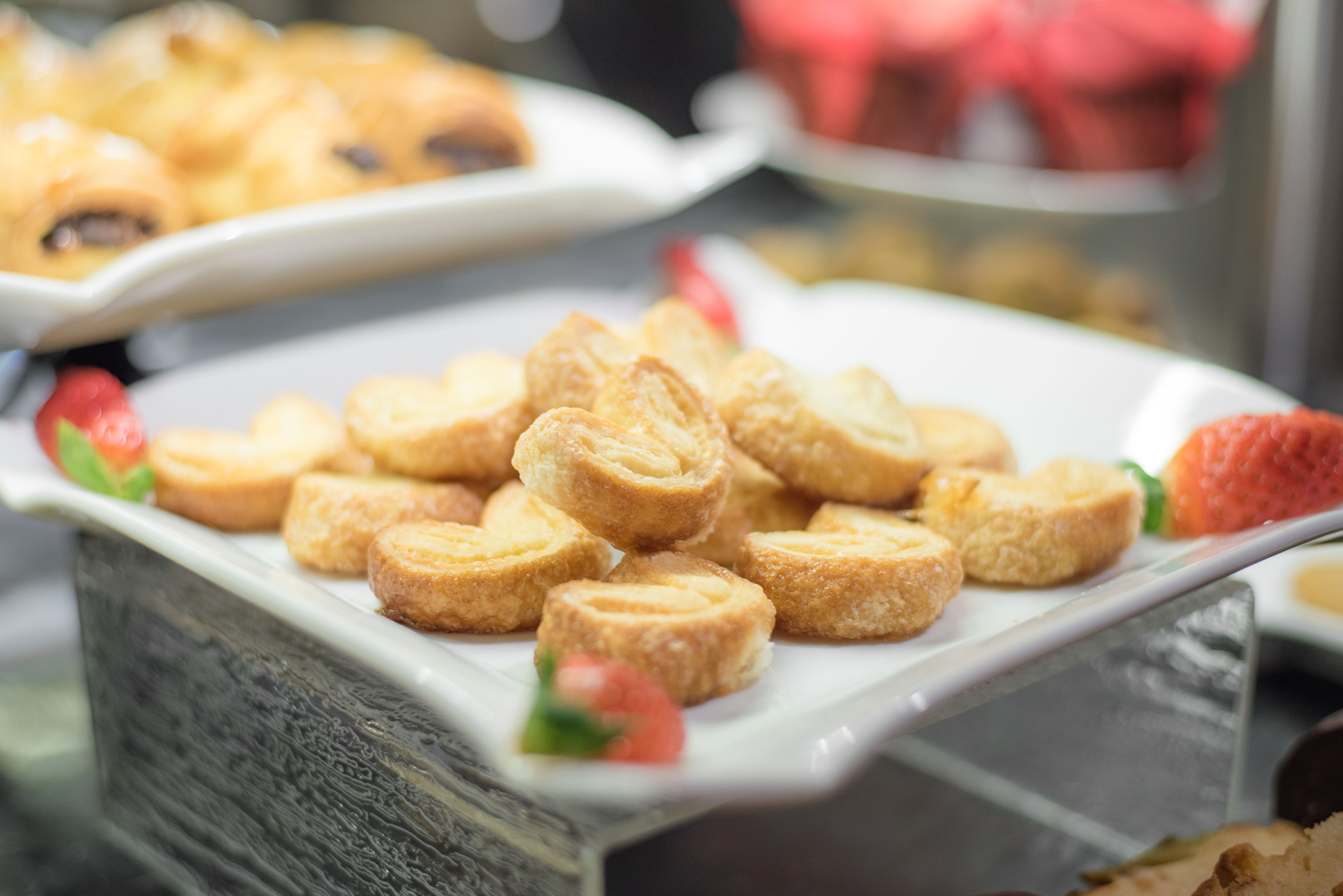 A buffet with various pastries and a strawberry garnish.