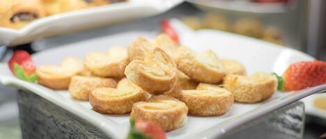 A buffet with various pastries and a strawberry garnish.