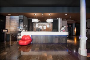 A reception area with a marble wall, a reception desk, and a red heart-shaped seating area.