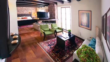 A modern living room with a fireplace, green chairs, a sofa, and a TV.