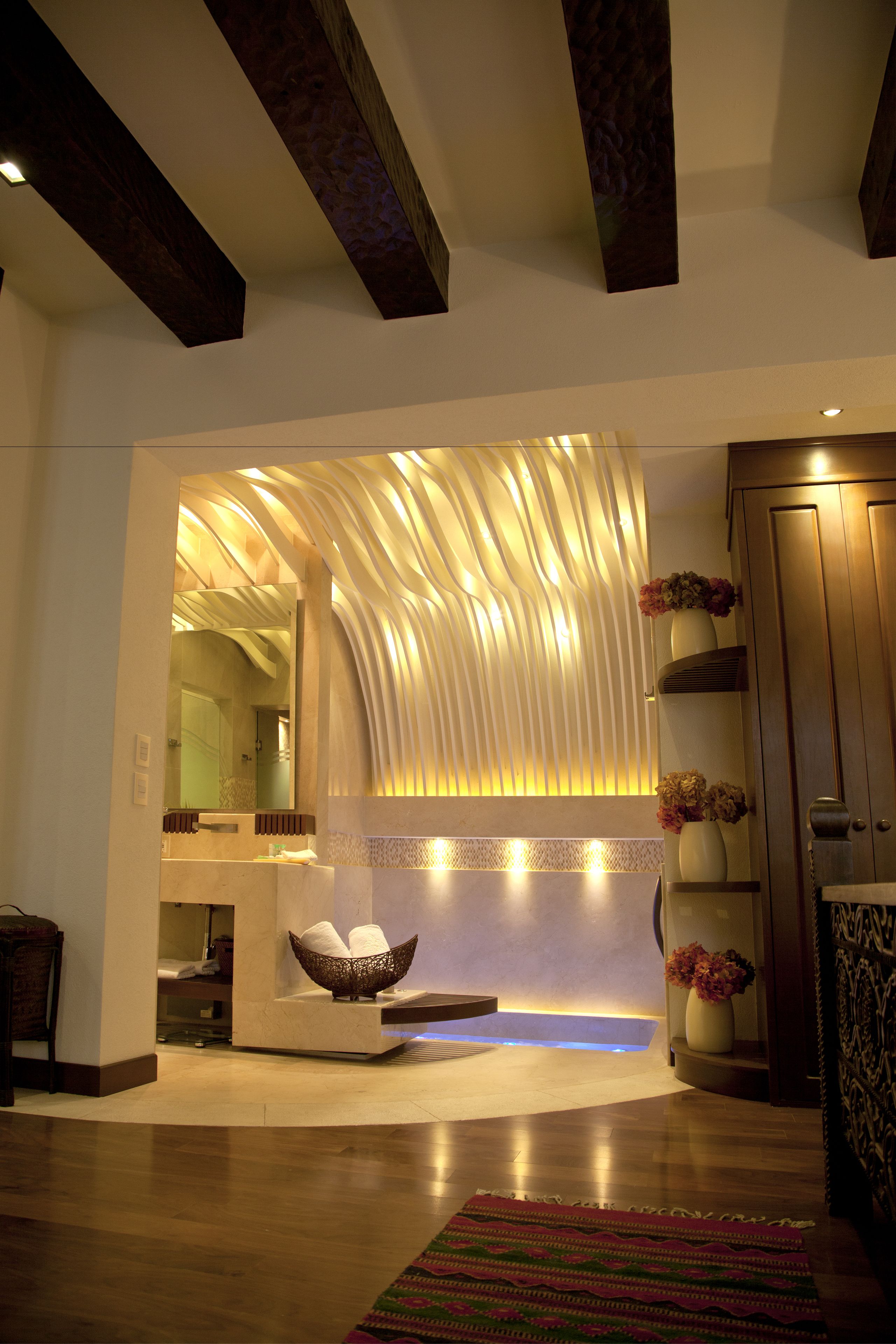 Un bagno moderno con una parete curva, uno specchio grande e un pannello decorativo.
