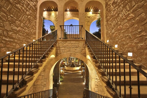 A stone staircase with a central fountain, flanked by arches and illuminated by wall-mounted lights. - Hotel de la Soledad (Morelia)