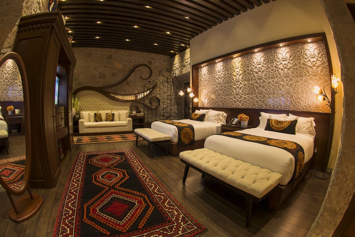 A luxurious bedroom with a large bed, a smaller sofa, and a bench.