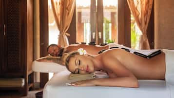 A massage therapy room with wooden furniture and a view of greenery outside.
