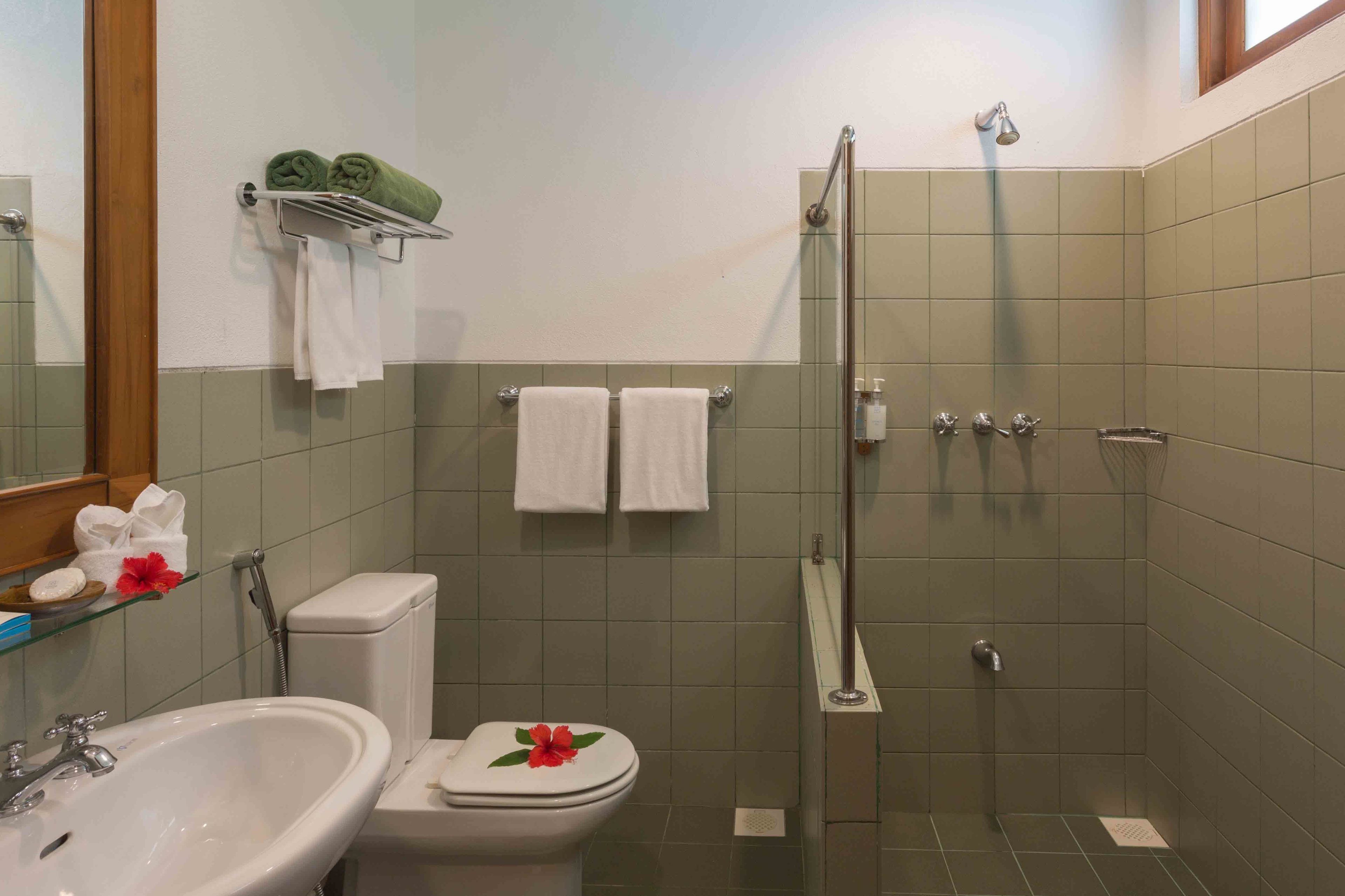 Egy fürdőszoba, amelyben WC, mosdókagyló és zuhanyzó található.