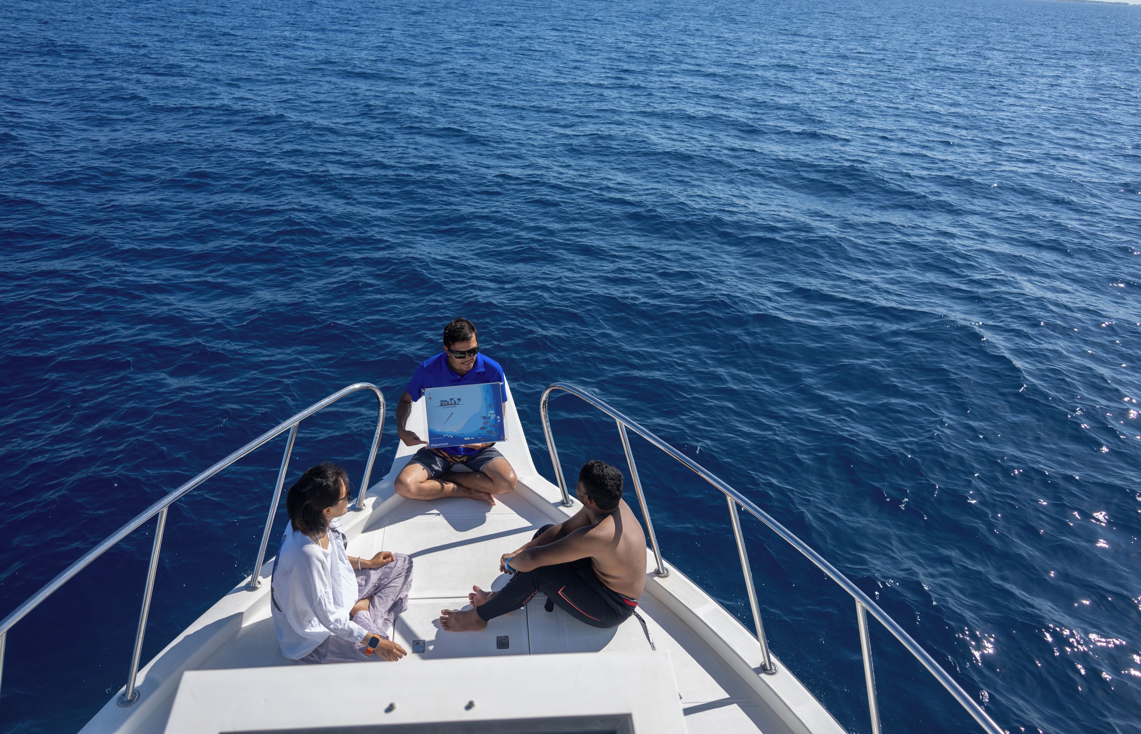 Trois personnes se trouvent sur un bateau, avec une vue sur l’océan.