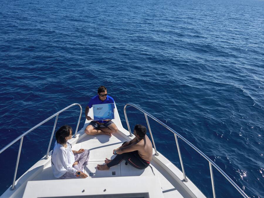 Trois personnes se trouvent sur un bateau, avec une vue sur l’océan.