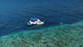 Un bote sobre aguas azul turquesa y un lecho marino rocoso.