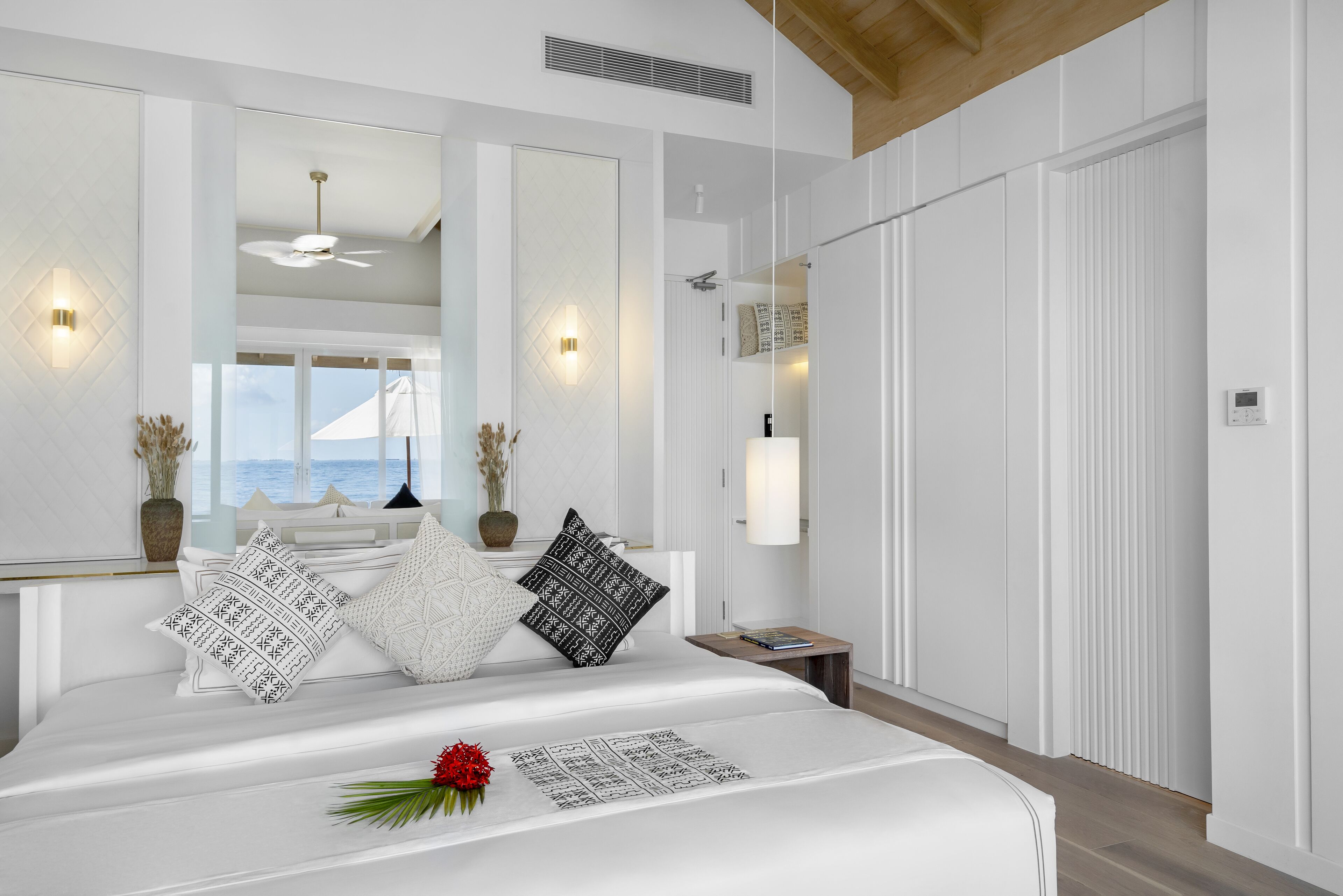 Un dormitorio moderno con una cama grande, vista al mar y un ventilador de techo.
