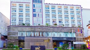 Un hotel de varios pisos con un logotipo de TTC destacado, un balcón con plantas y un letrero que indica que es un hotel en Can Tho.
