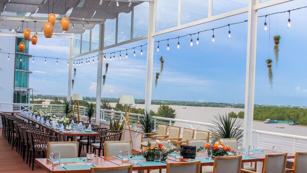 Un área de comedor al aire libre con mesas dispuestas para una comida, con vista a un río.