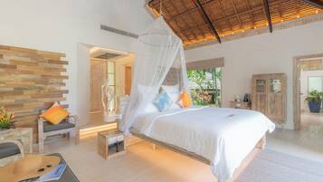A spacious bedroom with a large bed, a wooden headboard, a nightstand, a chair, and a potted plant.