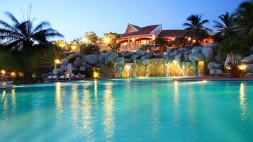 Una piscina al aire libre, sombrillas, sillones reclinables de piscina