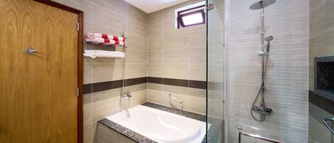 Un baño moderno con ducha de vidrio, puerta de madera y lavamanos integrado.