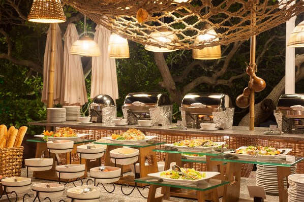 An outdoor buffet setup with various food stations, wicker furniture, and hanging lights. -  Phu Hai Beach Resort & Spa Phan Thiet (Phan Thiet)