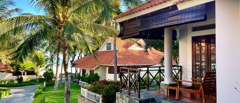 A resort with a covered outdoor seating area, stone steps, and palm trees.