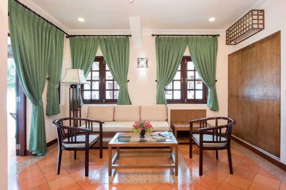 Una sala de estar con sofá, dos sillones, una mesa de centro y una lámpara.