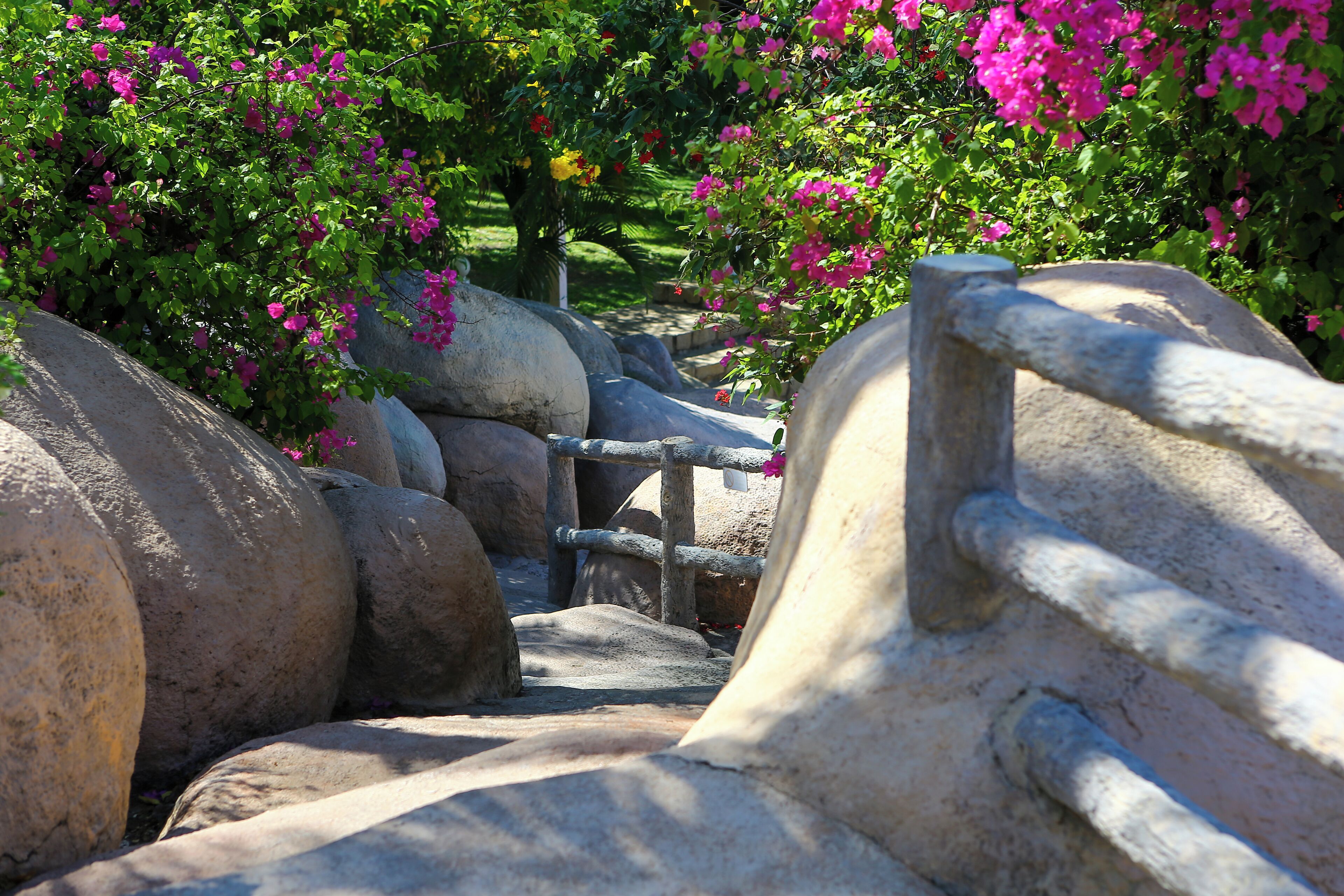 A stone pathway with large boulders and a metal railing.