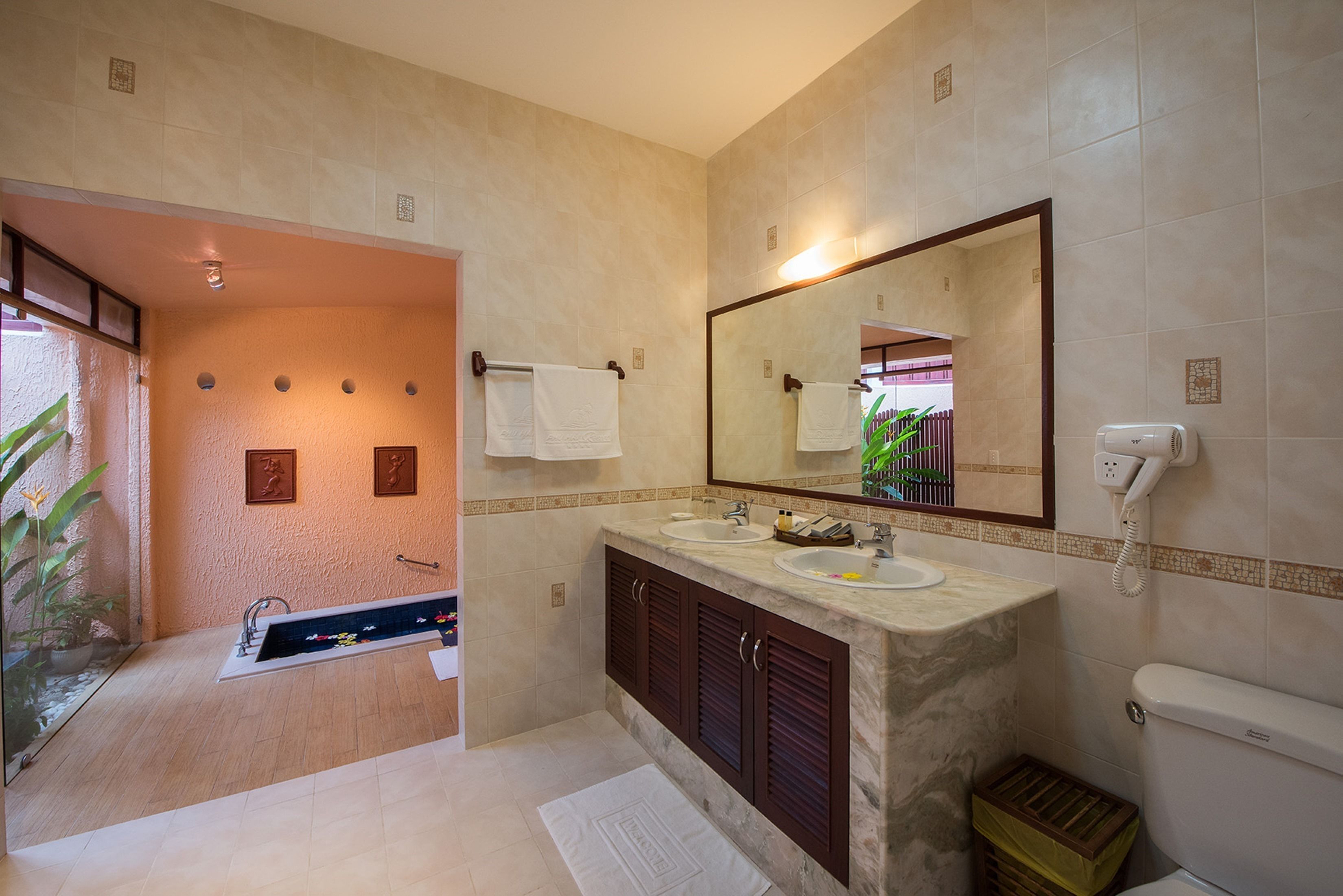 Un baño con tocador de mármol, un espejo grande y un inodoro.