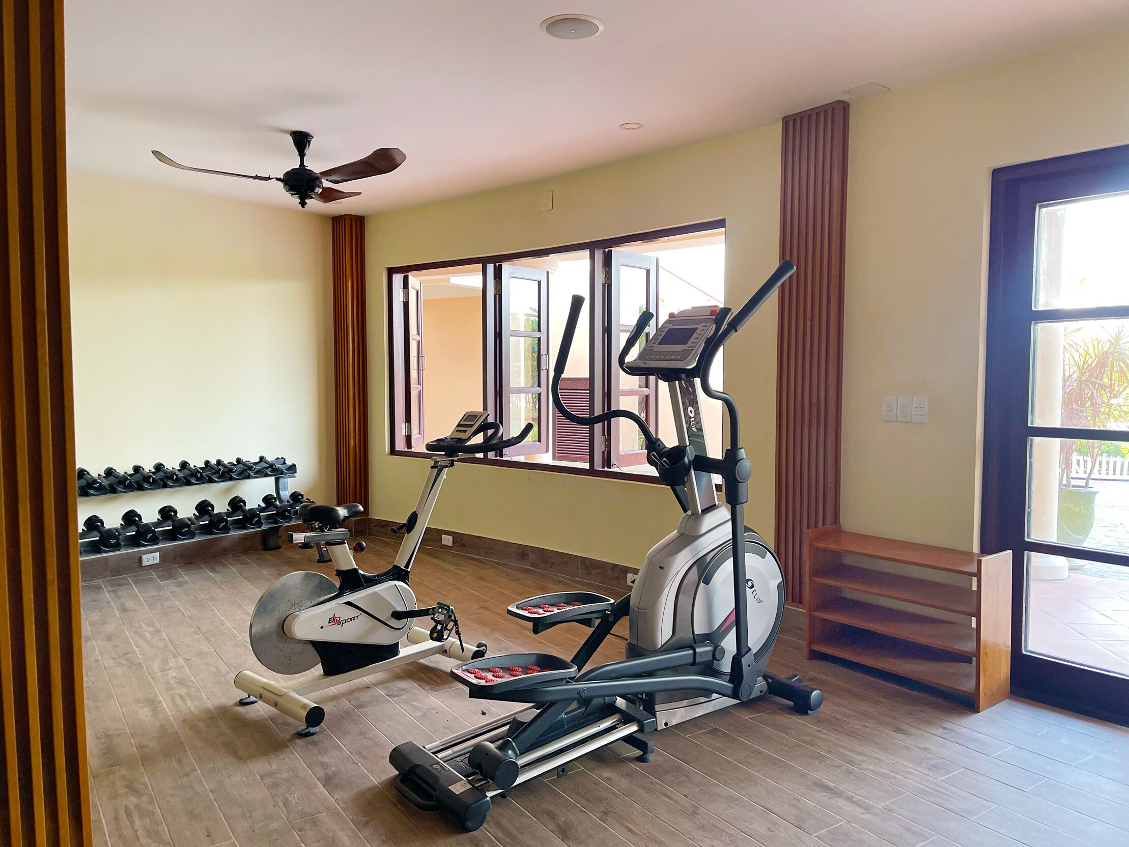 Une salle de sport équipée de matériel d’exercice, dotée d’un ventilateur de plafond et d’une fenêtre offrant une vue agréable.