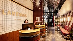 A reception area with a tiled wall, wooden reception desks, and a red leather couch. - Laneways by Ovolo (Melbourne)