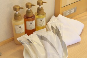 Ein Badezimmer-Waschtisch mit drei Flaschen Duschbadezusatz, einem weißen Handtuch und mehreren Packungen Taschentücher.