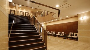 A hotel lobby with a staircase, seating area, and reception desk. - Chisun Hotel Hiroshima (Hiroshima)