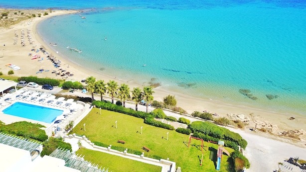 A beach resort with a swimming pool, sun loungers, and a view of the sea. - Saint George Hotel (Paros)