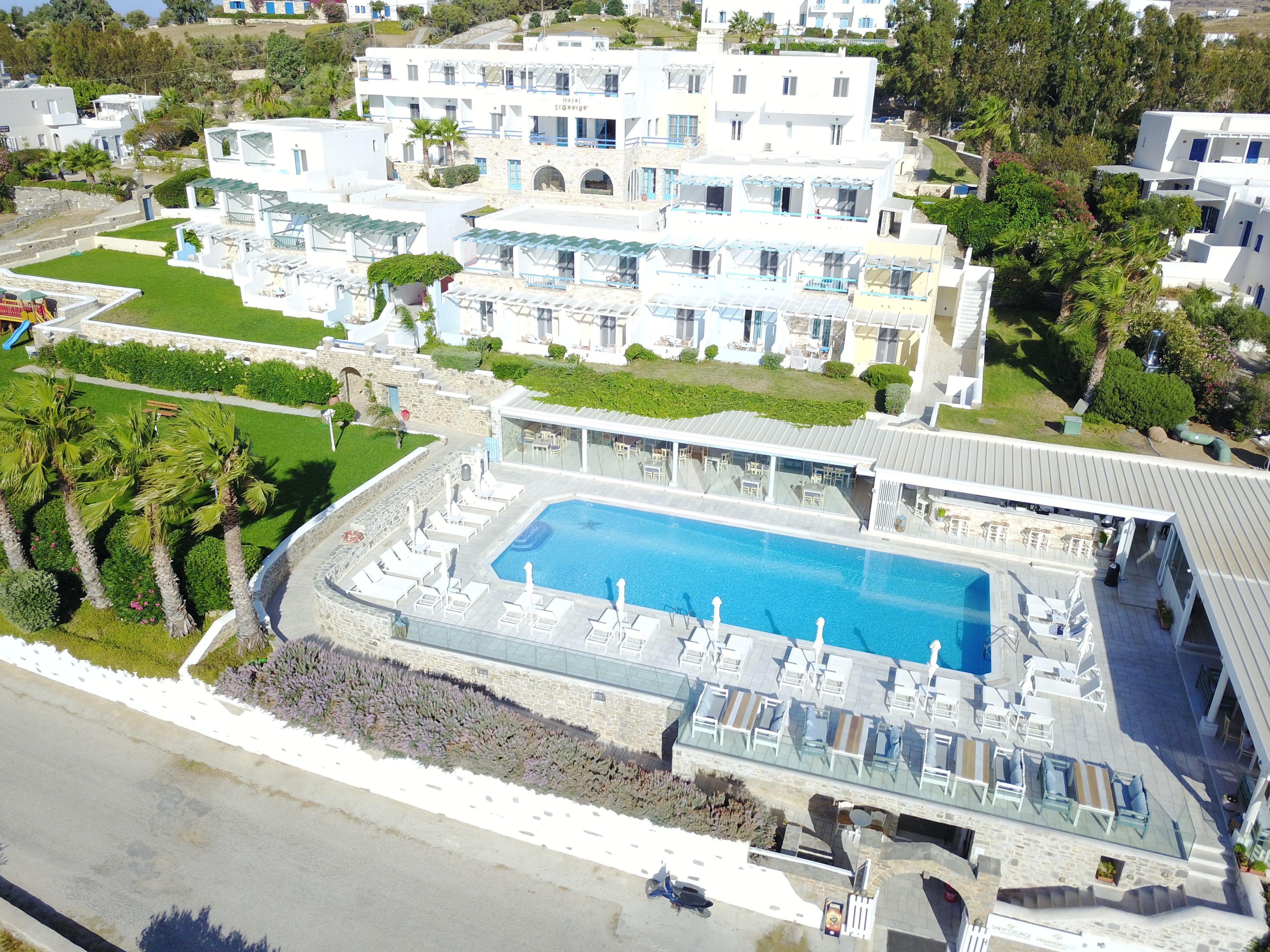 A large hotel with a swimming pool, multiple balconies, and a well-maintained garden.