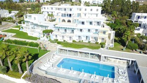 A large hotel with a swimming pool, multiple balconies, and a well-maintained garden.