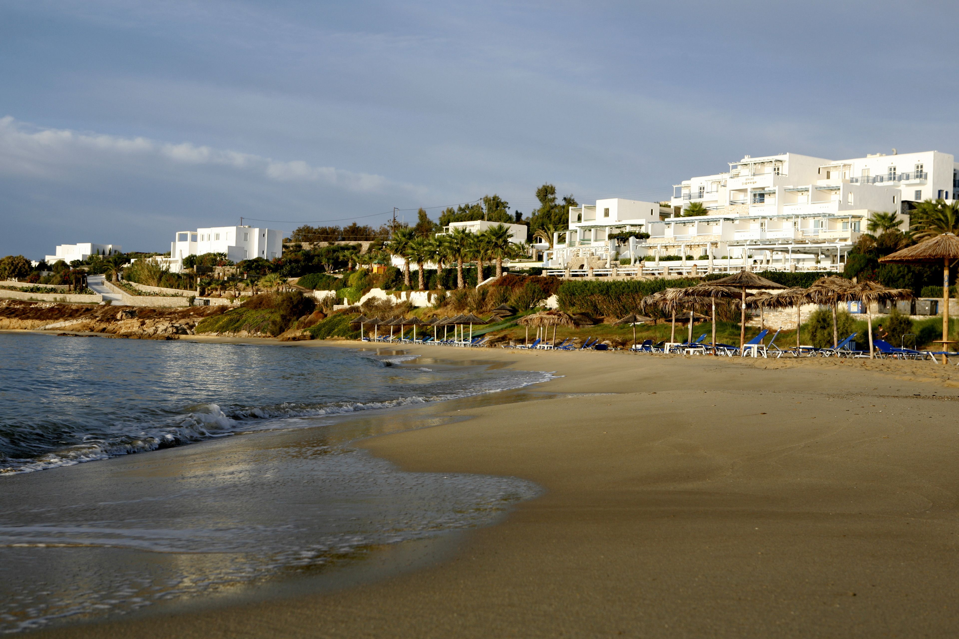 Una playa con edificios blancos al fondo, algunos con balcones.