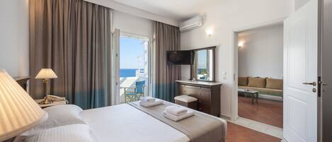 Una habitación de hotel con una cama, un escritorio, una televisión y vista al mar.