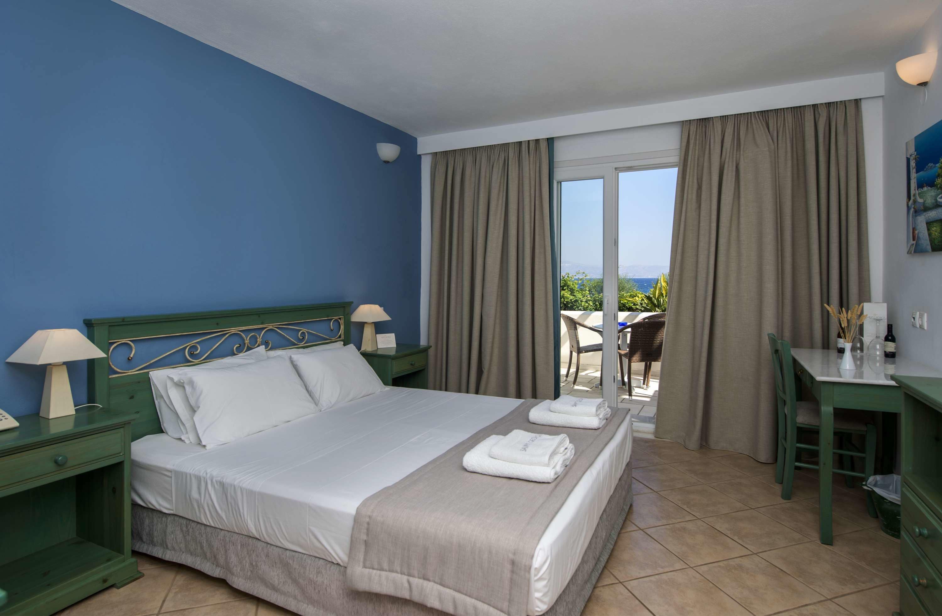 Ein Hotelzimmer mit einem großen Bett, einem Schreibtisch und Blick ins Freie.